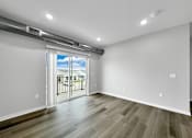 Thumbnail 17 of 69 - an empty living room with a sliding glass door to a balcony at Converge NW, Waukee  