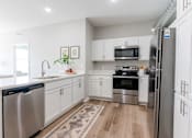 Thumbnail 4 of 69 - A kitchen with white cabinets and stainless steel appliances at Converge NW, Waukee, IA