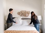 Thumbnail 13 of 42 - a man and woman making a bed in a bedroom at Forge65, Pleasant Hill, IA, 50327