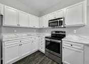 Thumbnail 9 of 50 - A kitchen with white cabinets and a black stove top oven. at Stonegate Crossing Apartments, Clive