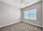 Thumbnail 11 of 50 - an empty bedroom with a ceiling fan and a window at Stonegate Crossing Apartments, IOWA, 50325