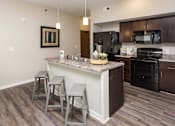 Thumbnail 15 of 50 - A kitchen with a granite countertop and bar stools. at Stonegate Crossing Apartments, Clive, 50325