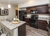 Thumbnail 17 of 50 - a kitchen with black appliances and a granite counter top at Stonegate Crossing Apartments, Clive