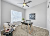 Thumbnail 16 of 57 - a room with a desk and a ceiling fan at Rialto Townhomes Apartments, Waukee, IA, 50263