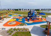 Thumbnail 43 of 57 - an aerial view of a playground with a blue slide at Rialto Townhomes Apartments, Waukee, IA