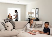 Thumbnail 14 of 57 - a woman sitting on a couch with a child reading a book at Rialto Townhomes Apartments, Iowa