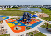 Thumbnail 42 of 57 - an aerial view of a playground and park with a river in the background at Rialto Townhomes Apartments, Waukee
