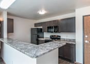 Thumbnail 25 of 33 - a kitchen with black appliances and a granite counter top at Penbrooke Place Apartments, Sioux Falls