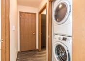 Thumbnail 23 of 33 - A washing machine is in a small room with a wooden door at Penbrooke Place Apartments, Sioux Falls, SD