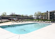 Thumbnail 27 of 33 - a swimming pool with chairs and a fence around it at Penbrooke Place Apartments, Sioux Falls, SD