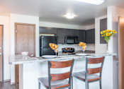 Thumbnail 26 of 33 - A kitchen with a black refrigerator, black microwave, and black oven at Penbrooke Place Apartments, South Dakota, 57106