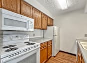 Thumbnail 8 of 33 - A kitchen with white appliances and wooden cabinets at Penbrooke Place Apartments, Sioux Falls, South Dakota