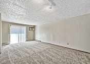 Thumbnail 5 of 33 - A room with a carpeted floor and a door leading to a balcony at Penbrooke Place Apartments, Sioux Falls