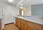 Thumbnail 19 of 33 - A kitchen with wooden cabinets and a white fridge at Penbrooke Place Apartments, Sioux Falls, SD, 57106