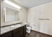 Thumbnail 18 of 33 - A bathroom with a sink, toilet, and mirror at Penbrooke Place Apartments, Sioux Falls