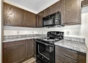 Thumbnail 13 of 33 - a kitchen with black appliances and wood cabinets at Penbrooke Place Apartments, South Dakota, 57106
