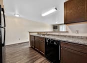 Thumbnail 16 of 33 - A kitchen with a black oven and wooden cabinets at Penbrooke Place Apartments, Sioux Falls, 57106