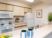 Thumbnail 9 of 33 - A kitchen with a white countertop and a white refrigerator at Penbrooke Place Apartments, Sioux Falls