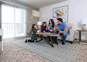 Thumbnail 20 of 33 - A family of four is sitting on a couch in a living room at Penbrooke Place Apartments, Sioux Falls, SD