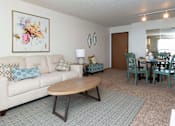 Thumbnail 22 of 33 - A living room with a white couch and a wooden coffee table at Penbrooke Place Apartments, Sioux Falls, South Dakota