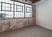 Thumbnail 6 of 25 - A room with a large window and a brick wall at Spaulding Lofts Apartments, Grinnell, IA, 50112