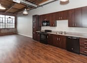 Thumbnail 2 of 25 - A kitchen with wooden floors and dark brown cabinets at Spaulding Lofts Apartments, Grinnell, IA