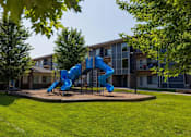 Thumbnail 18 of 35 - A blue slide in a playground in front of a building.