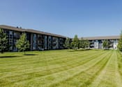 Thumbnail 27 of 35 - A large grassy field in front of apartment buildings.