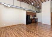 Thumbnail 4 of 13 - A kitchen area with wooden floors and a black refrigerator.at Riverpoint Lofts, Des Moines, IA  