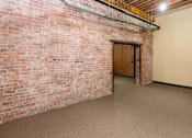 Thumbnail 6 of 13 - A room with a brick wall and a door.at Riverpoint Lofts, Des Moines  