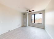 Thumbnail 10 of 27 - an empty living room with a ceiling fan and a large window at Canary Lofts, Des Moines, IA