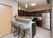 Thumbnail 16 of 31 - spacious kitchen with stainless steel appliances and a bar with three stools at Lake Shore Apartments, Ankeny