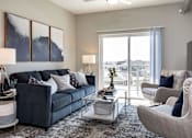 Thumbnail 3 of 31 - a living room with a blue couch and a glass coffee table at Lake Shore Apartments, Ankeny, Iowa