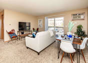 Thumbnail 3 of 22 - A living room with a white couch, a white chair, a white dining table and chairs, a television, and a potted plant at Lake Shore Park, Iowa