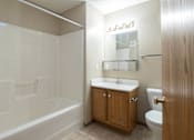 Thumbnail 5 of 10 - A bathroom with a white tub, sink, and toilet at Peach Tree Apartments, IA, 50021