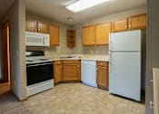 Thumbnail 4 of 10 - a kitchen with white appliances and wooden cabinets at Peach Tree Apartments, Ankeny, IA