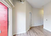 Thumbnail 12 of 31 - A room with a white door and a window with a red shade at Vue Apartments, Des Moines, IA 50309