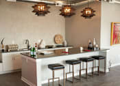 Thumbnail 22 of 31 - a kitchen with a counter and some stools at Vue Apartments, Des Moines, IA 50309