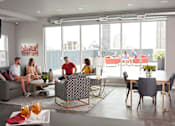 Thumbnail 28 of 31 - A group of people are sitting in a modern living room at Vue Apartments, Des Moines