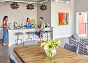 Thumbnail 24 of 31 - people in a living room and kitchen with a table and chairs at Vue Apartments, Des Moines, IA 50309