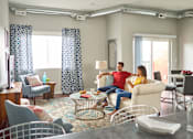 Thumbnail 1 of 31 - a man and woman sitting on a couch in a living room at Vue Apartments, Iowa, 50309