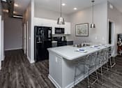 Thumbnail 4 of 31 - A modern kitchen with a black fridge and white countertops at Vue Apartments, Iowa