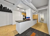 Thumbnail 5 of 50 - A white reception desk with a black counter top is in the middle of a room with wood flooring at The Des Moines Building Apartments, Des Moines