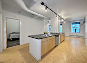 Thumbnail 10 of 50 - A kitchen with wooden floors and a black countertop at The Des Moines Building Apartments, IA, 50309