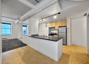 Thumbnail 7 of 50 - A kitchen with a white island and wooden cabinets at The Des Moines Building Apartments, Iowa, 50309