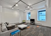 Thumbnail 11 of 50 - A living room with a grey couch, a white coffee table, and a television at The Des Moines Building Apartments, IA, 50309