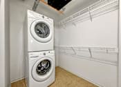 Thumbnail 12 of 50 - A white dryer and washer are stacked on top of each other in a small laundry room at The Des Moines Building Apartments, Iowa