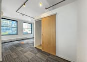 Thumbnail 33 of 50 - A room with a wooden door and grey carpet at The Des Moines Building Apartments, Des Moines