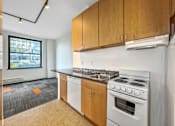 Thumbnail 28 of 50 - A kitchen with a white stove and wooden cabinets at The Des Moines Building Apartments, Des Moines, IA, 50309