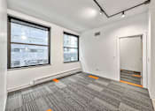 Thumbnail 4 of 50 - A room with grey carpet and windows overlooking a city at The Des Moines Building Apartments, Des Moines, IA, 50309